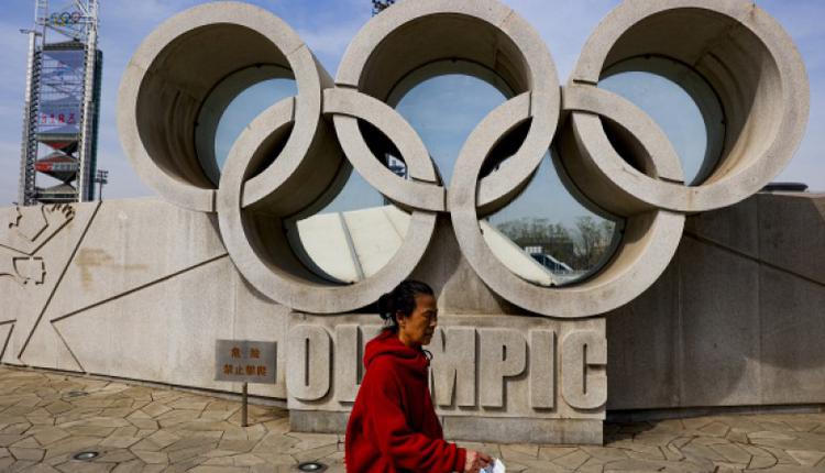 一名女子在北京奥林匹克公园走过五环标志。